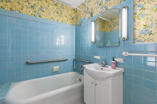 The upper level full bath features a vanity sink, mirror with wall lights, and bold blue tile walls.