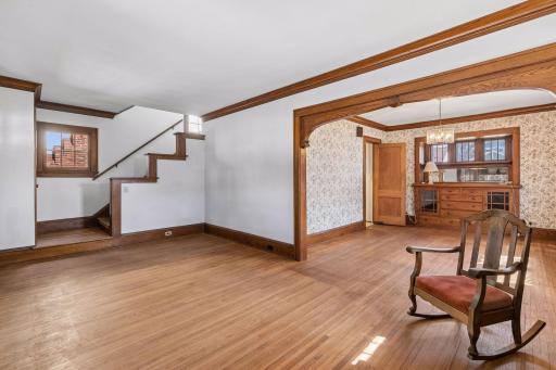 Beautifully framed archway opens to the dining area, featuring seamless hardwood flooring and classic crown molding.