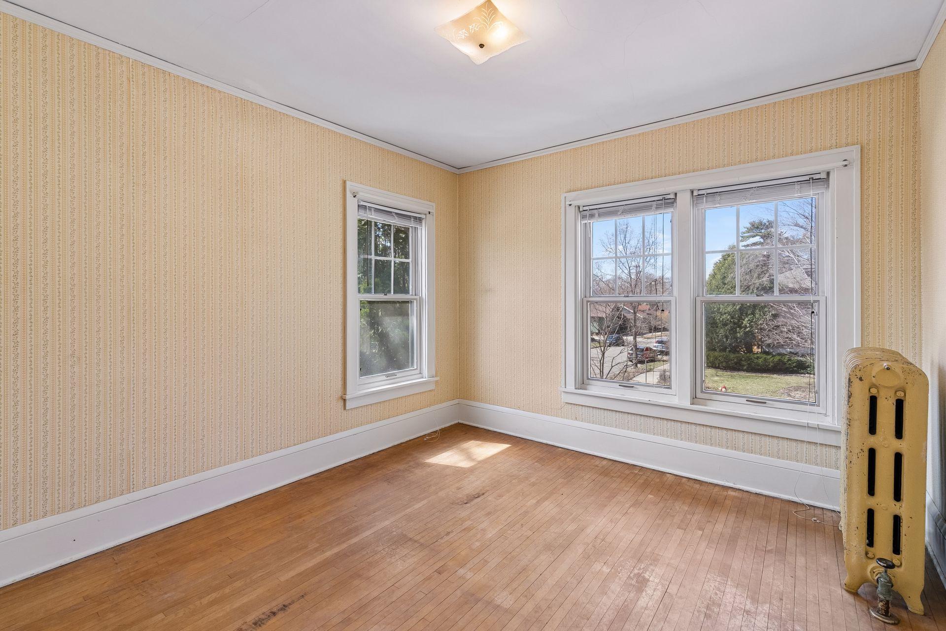 Spacious third upper level bedroom with hardwood floors, three windows and overhead lighting.
