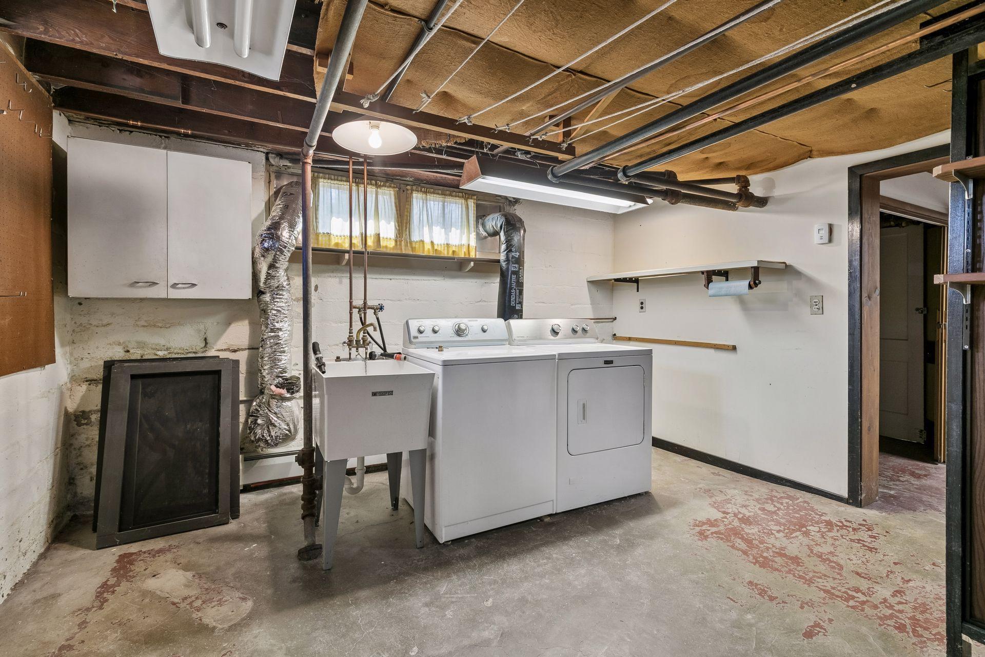 Lower level laundry with generous workspace, a utility sink and cabinets. Access the 1/4 bath nearby.