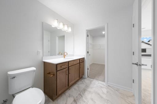 Owner's Bathroom features stained cabinets with gold fixtures and hardware with attached walk-in closet - for illustrative purposes only