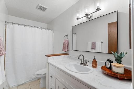 Spacious primary bathroom with new oversized vanity (2024) and modern light fixtures.