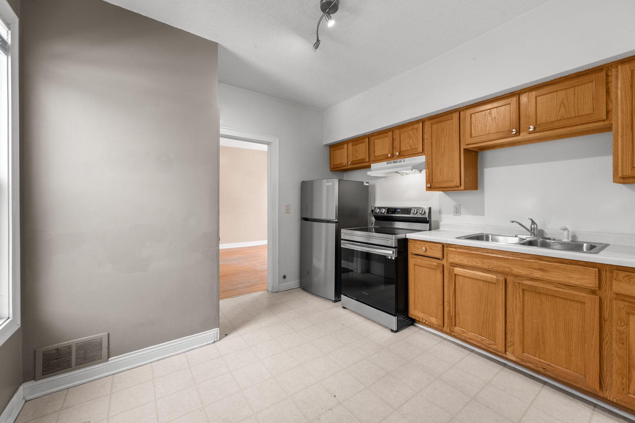 Back unit kitchen features an open layout with a new refrigerator and stove/oven