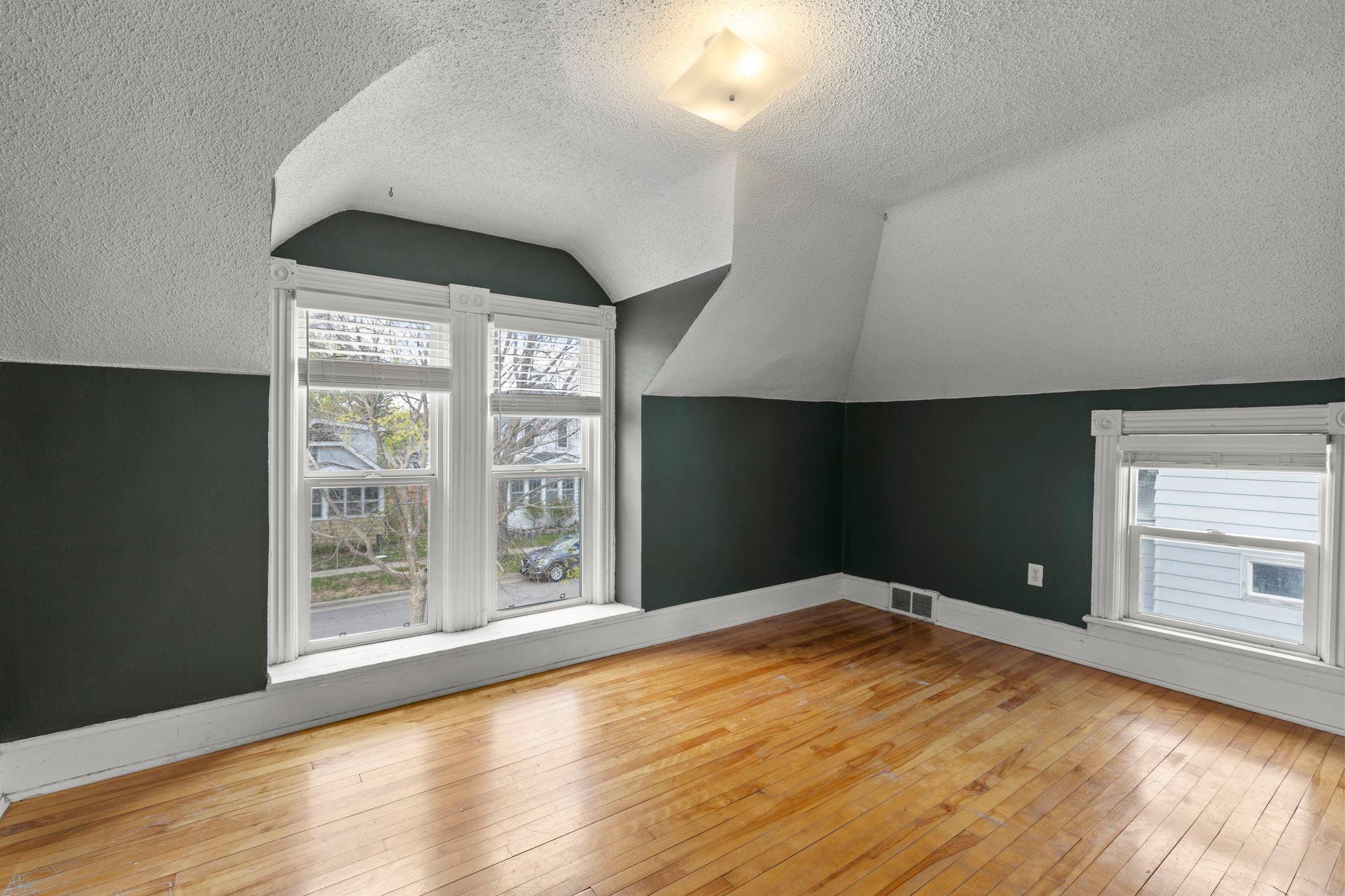 Upper level primary bedroom with beautiful hardwood floors, newer wood shutter blinds and plenty of light