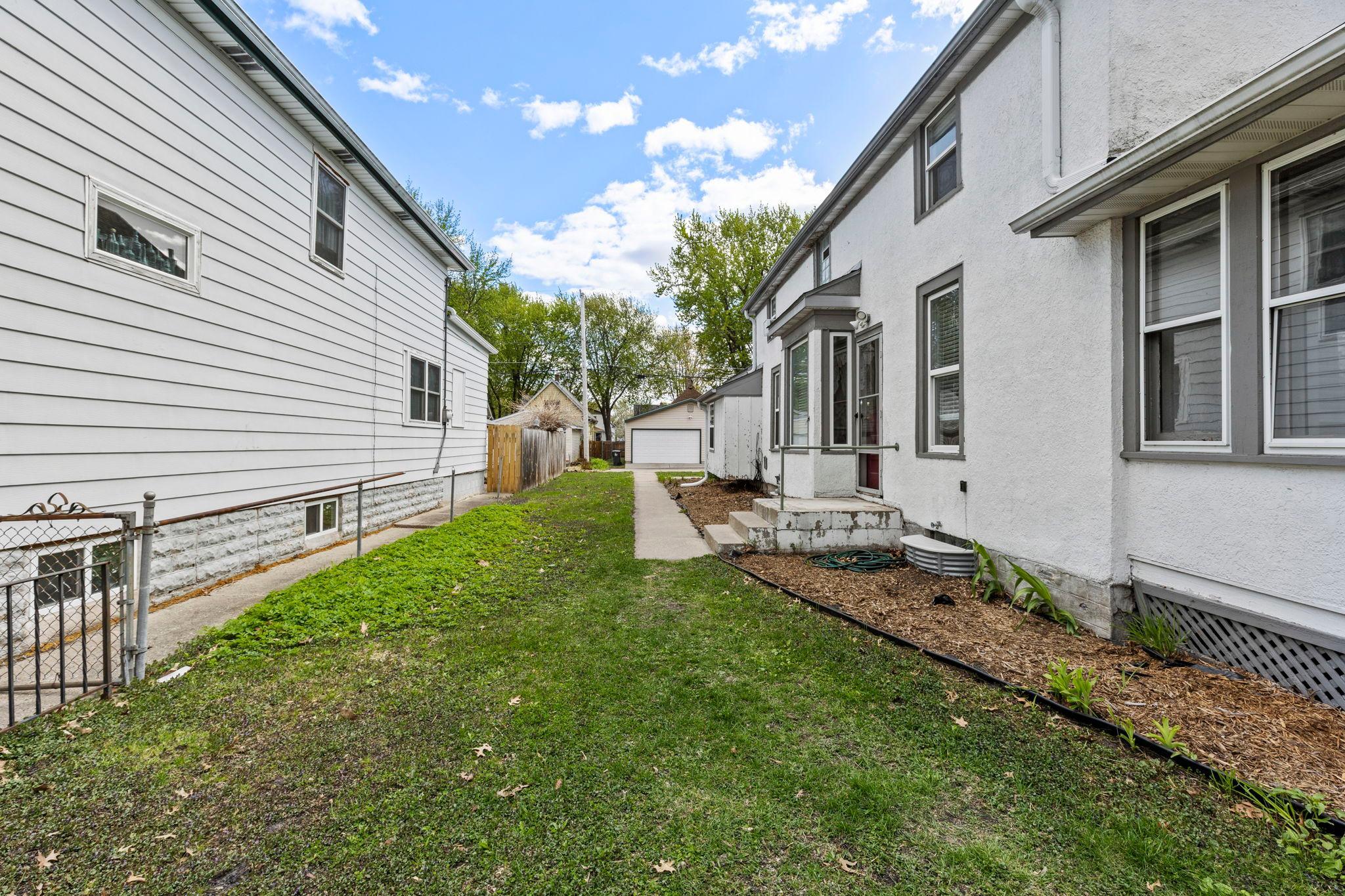 Outside, a sidewalk leads from the parking pad up to the side entrance of the front unit
