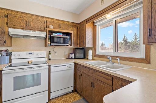 Kitchen with white Whirlpool and GE appliances and large window.