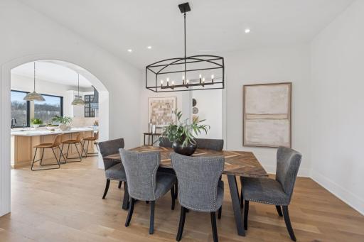 Sophisticated dining space with statement chandelier, warm hardwood flooring, and graceful archway opening to the kitchen.