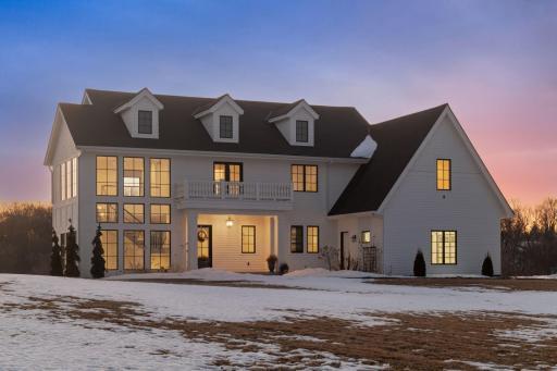Elegant twilight view of this custom home featuring classic architecture, expansive windows, and warm interior glow.
