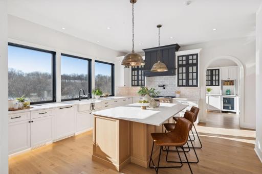 Designed for entertaining, the kitchen offers a large island with seating, generous prep space, and convenient access to the support kitchen.