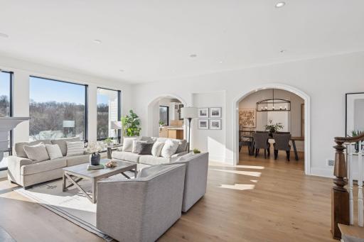 Light-filled great room with expansive windows, beautiful hardwood flooring, and graceful archways that flow seamlessly into the dining space.