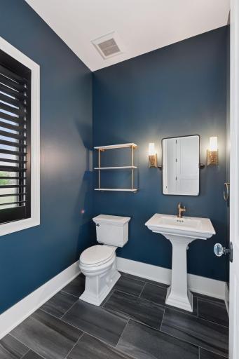 Designer powder bath with rich accent wall color, pedestal sink, and updated lighting creating a polished look.