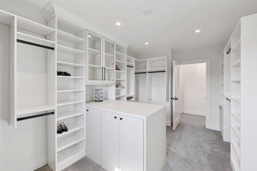 Stunning boutique-style walk-in closet with custom cabinetry, display storage, and a center island worthy of a private dressing suite.