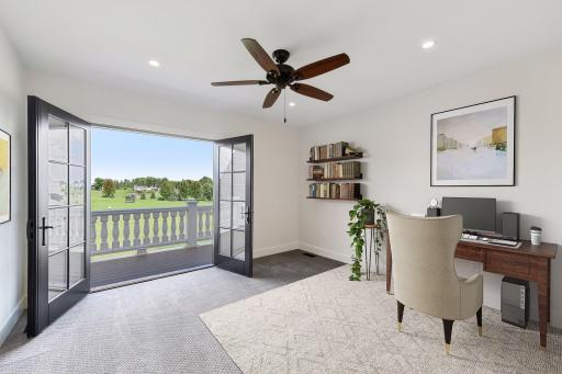 Beautiful bedroom or office with French doors opening to a balcony and expansive views of the surrounding landscape (virtually staged).