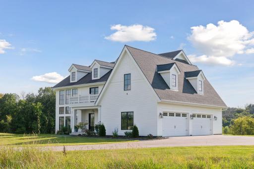 Striking exterior featuring elegant rooflines, dormer windows, and a spacious driveway setting.