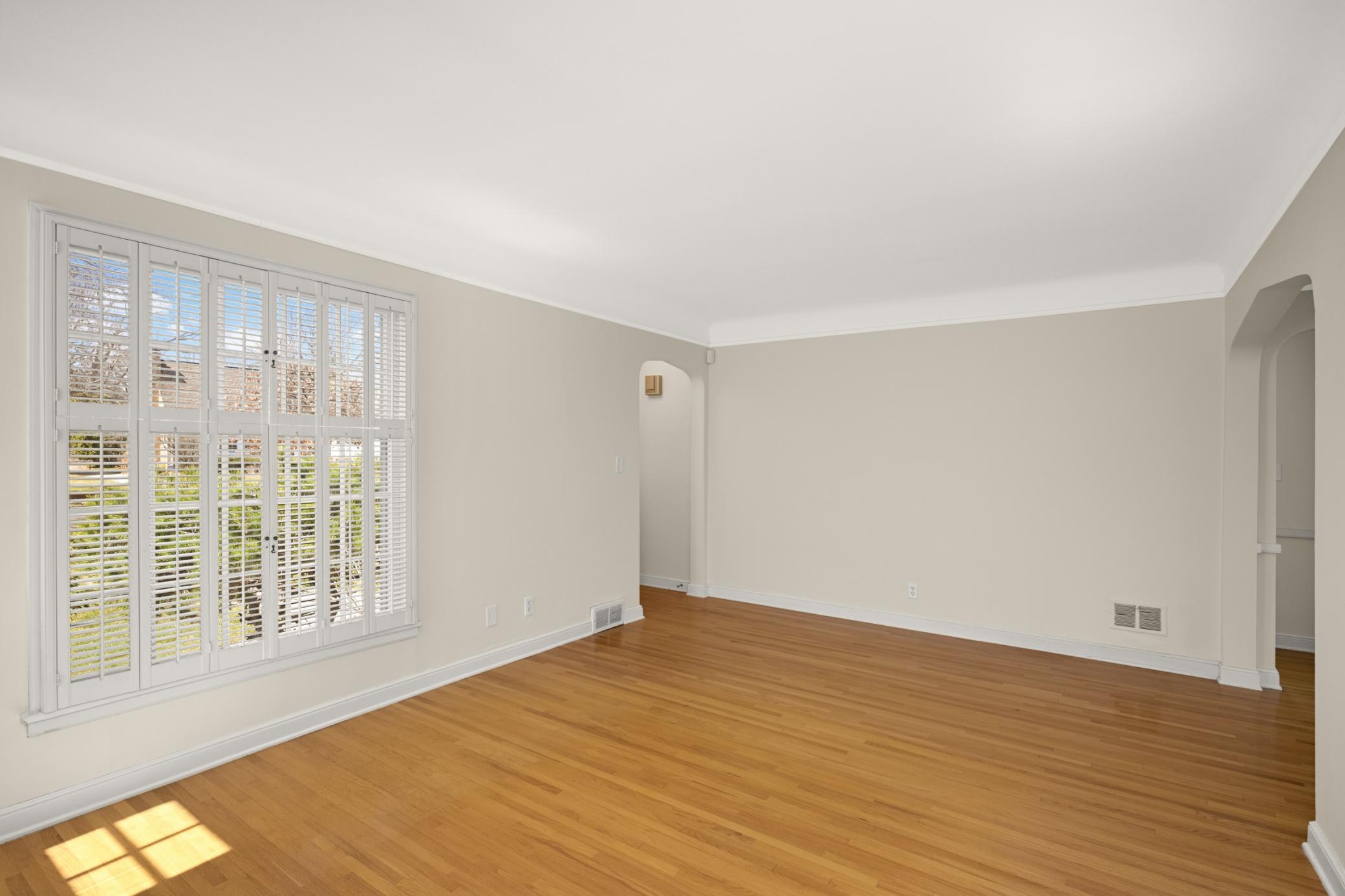 Living room has beautiful hardwood floors, coved ceilings and arched doorways
