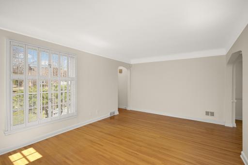 Living room has beautiful hardwood floors, coved ceilings and arched doorways