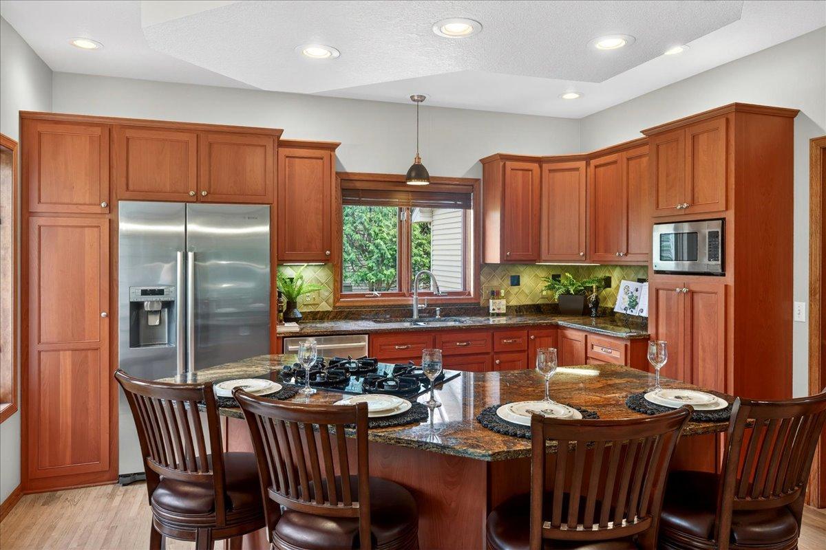 Custom Kitchen w/cherry cabinets, stainless steel appliances and window above sink with updated pendant lighting.
