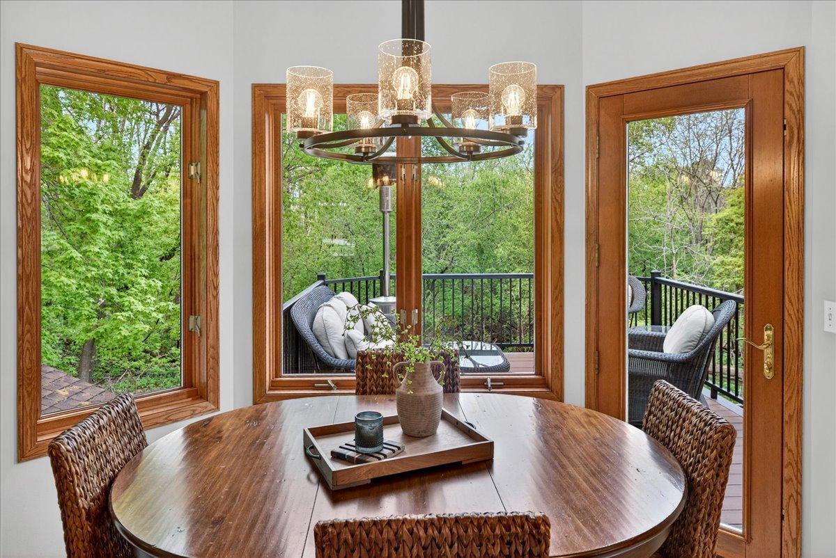 Bay window in informal dining area offers pristine, wooded views. There is an updated lighting fixture above table.