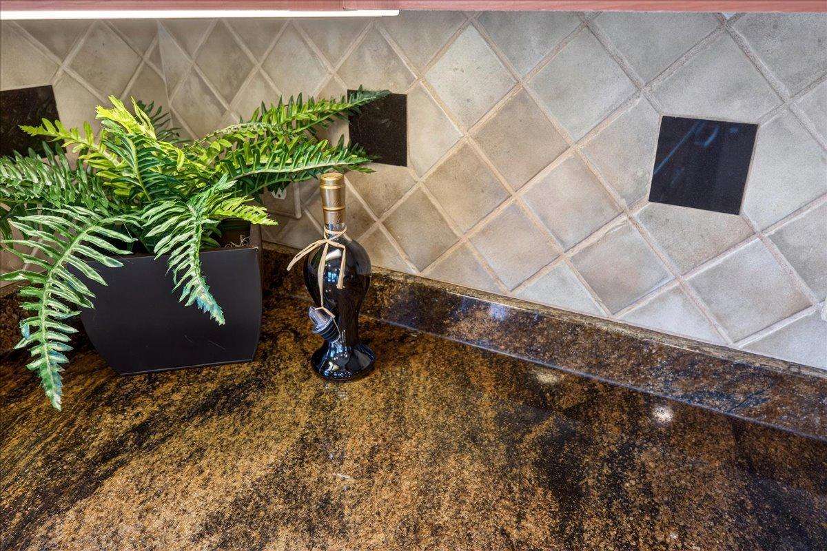 Kitchen countertops have beautiful granite. The tile backsplash is accented with decorative inserts.