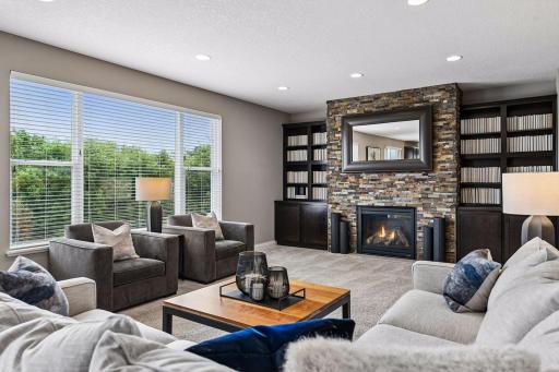 Family room on the main floor with stacked stone fireplace with large windows for natural light