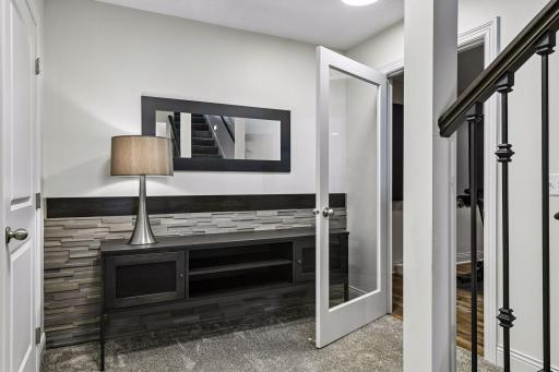 Landing at bottom of steps to basement with entry door to home gym