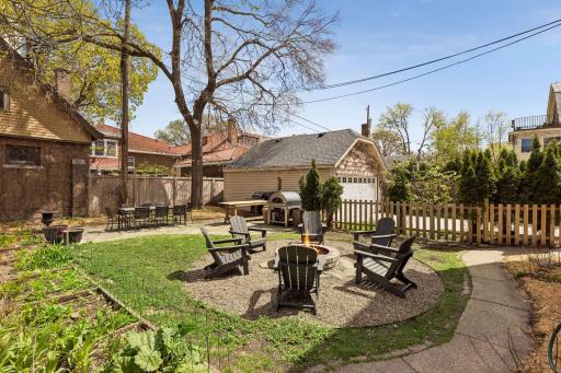 Additional view of the backyard showcasing the detached two-car garage, patio area, and multiple spaces for outdoor dining and gathering.