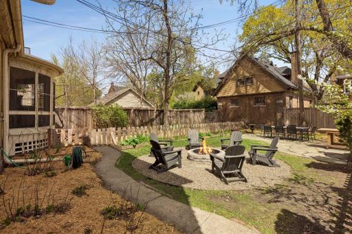 Inviting backyard with a fire pit seating area, patio, and a partially fenced dog run, offering a great setting for outdoor gatherings and pet-friendly living.