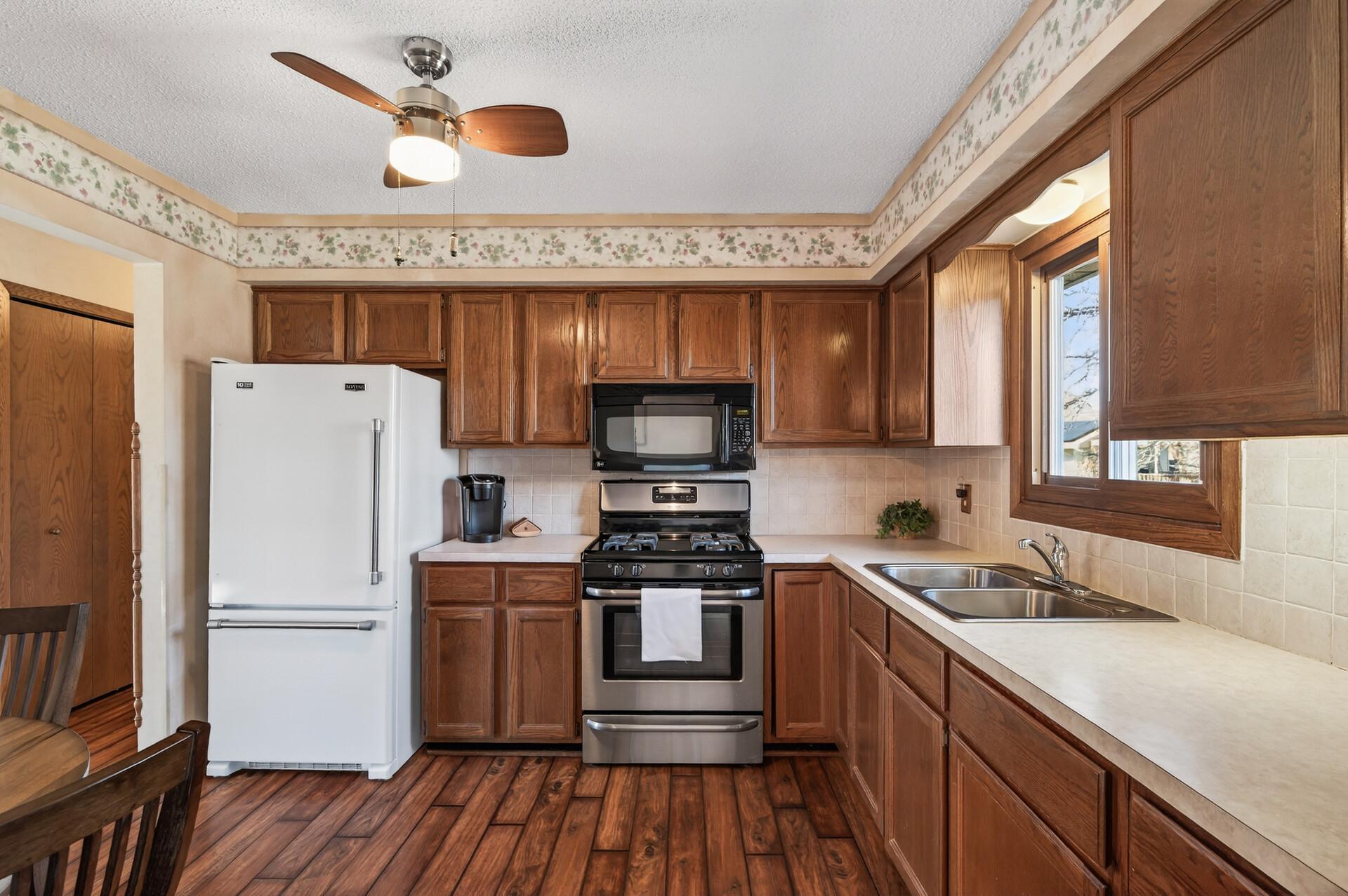 The kitchen provides abundance of neutral counter space & storage, stainless range & microwave and a ceiling fan to keep air moving.