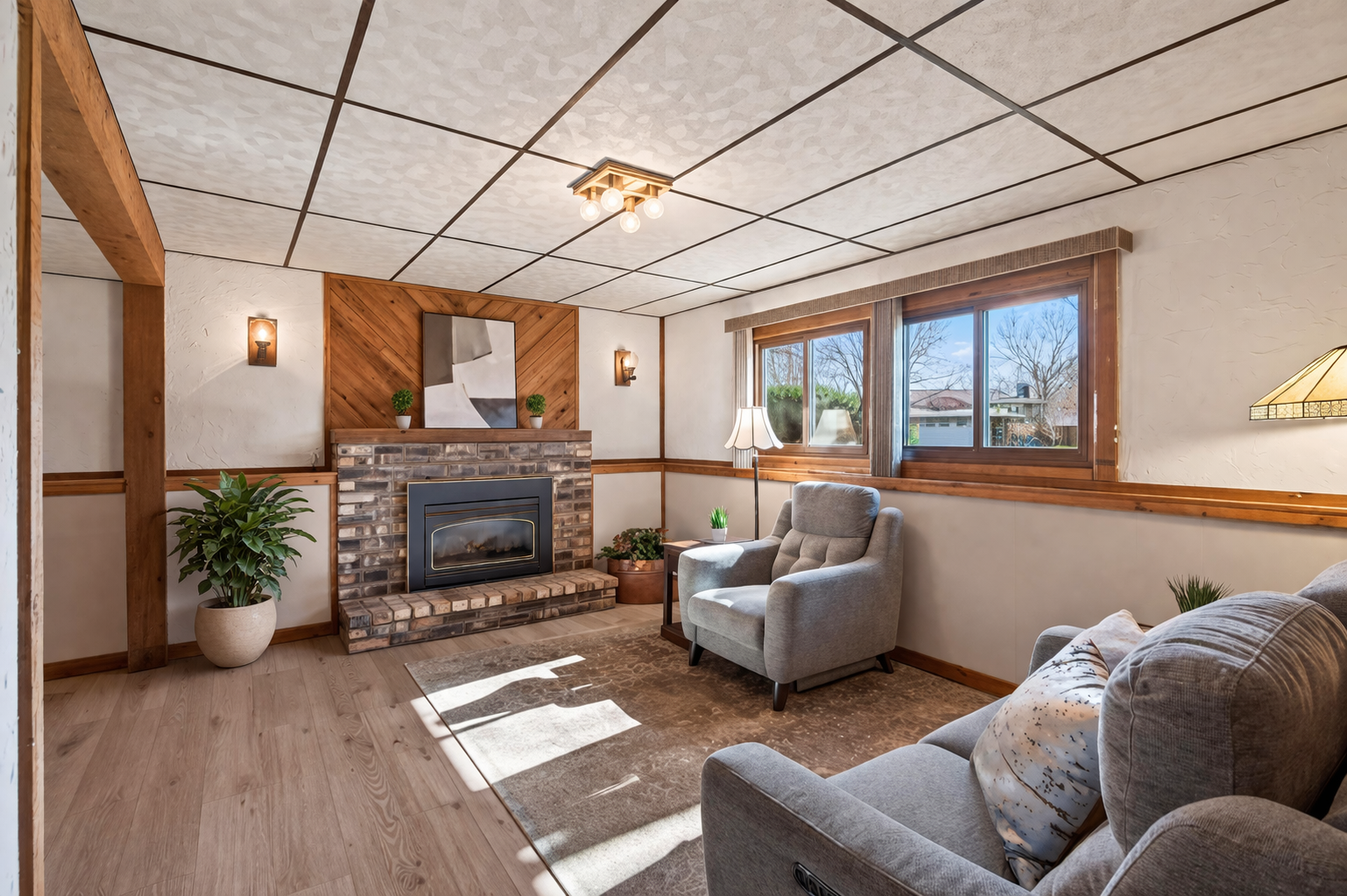 The second living space in the lower level features a brick fireplace, wall sconces and rustic accent wall for a warm & cozy feel.