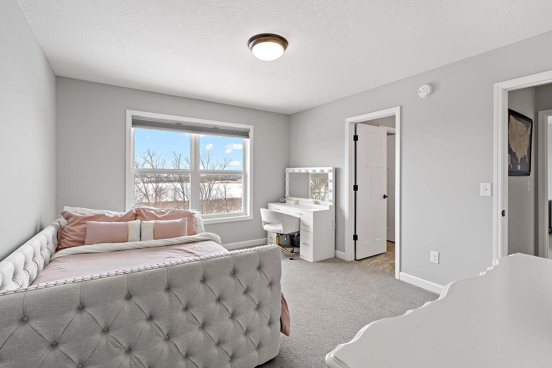 This inviting bedroom features a spacious walk-in closet and direct access to an adjoining bathroom, combining convenience with smart design for shared or guest living.