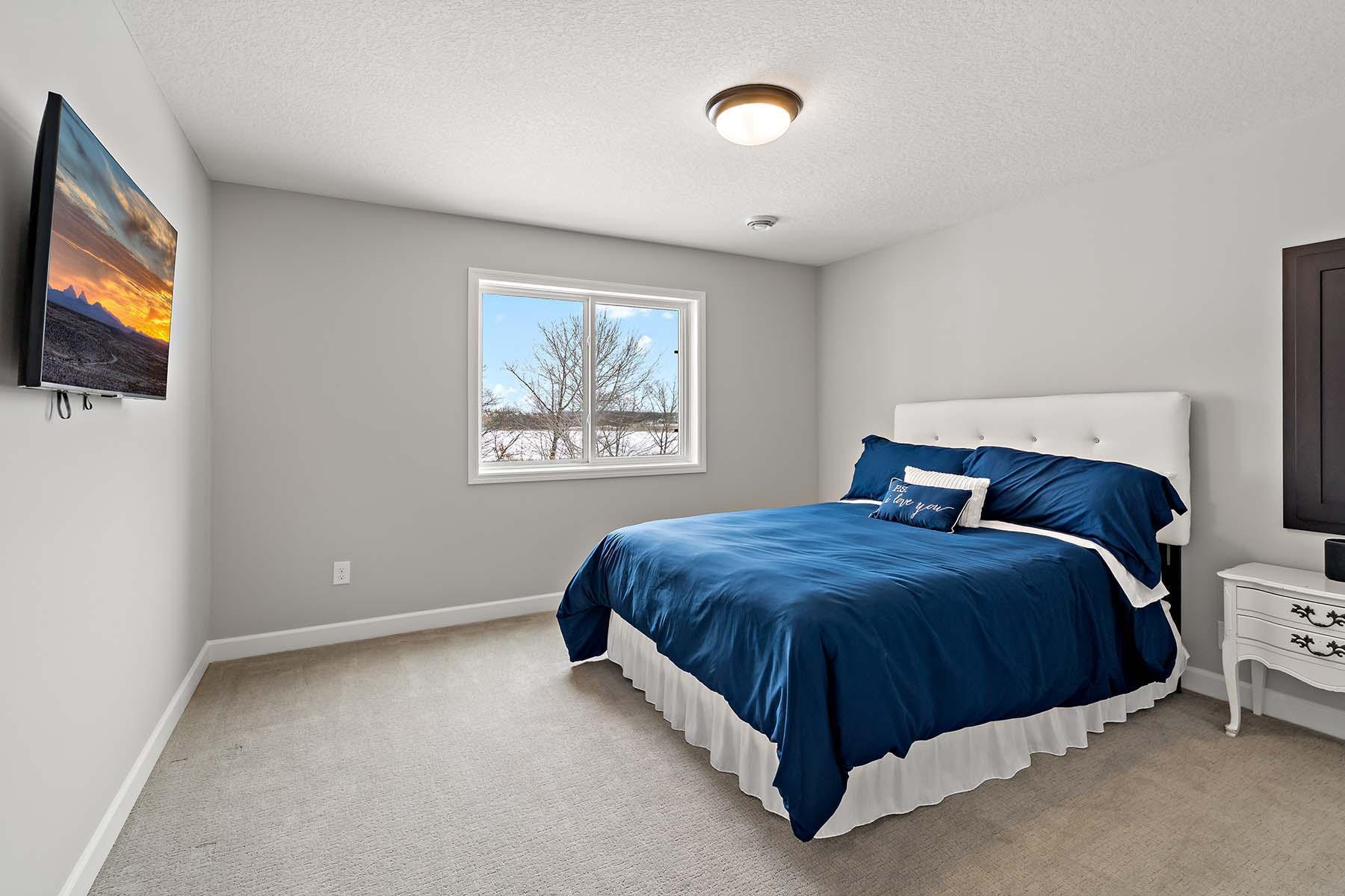 This private lower-level bedroom has a spacious walk-in closet and easy access to a 3/4 bathroom located just across the hall, offering comfort and convenience for guests or family members.