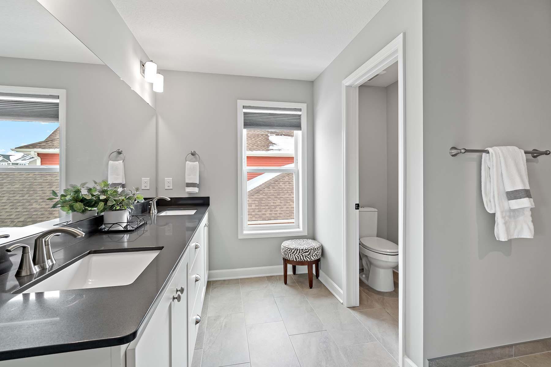 Designed for both style and functionality, the primary bathroom features a double vanity, a private water closet, and a luxurious dual-head tiled step-in shower. The thoughtful layout and elegant finishes create a relaxing and practical retreat.