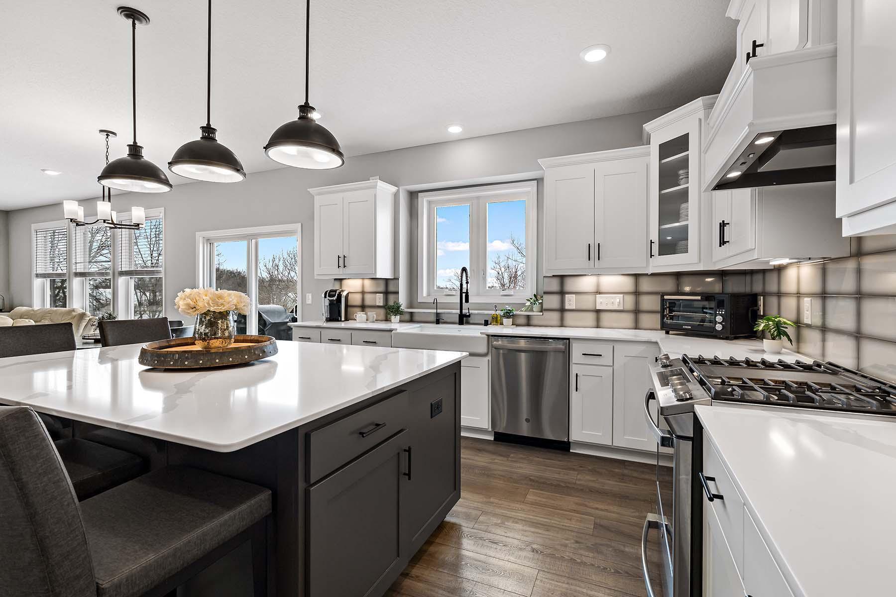 Featuring stainless steel appliances, this well-equipped kitchen includes a gas range, built-in exhaust hood, and a WiFi-enabled wall oven. Undercabinet lighting perfectly accents the tile backsplash.