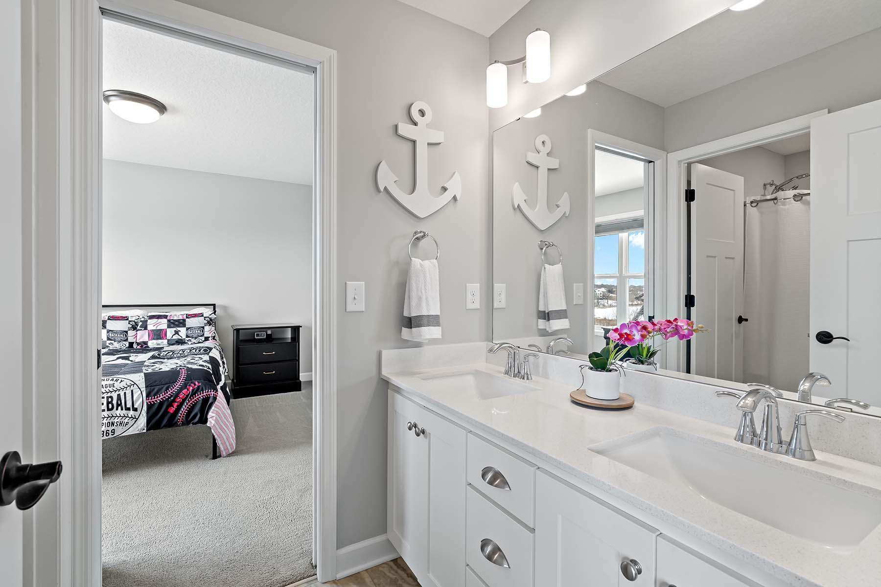 Designed for shared use, this adjoining bathroom features a double vanity, a separate water closet, and a combination tub and shower.