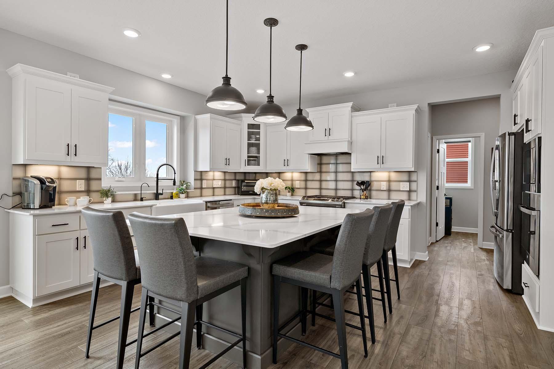 The kitchen is truly a standout space, featuring an oversized island with seating. Elegant quartz countertops elevate the space, while an abundance of cabinetry provides exceptional storage, combining style & functionality in the heart of the home.