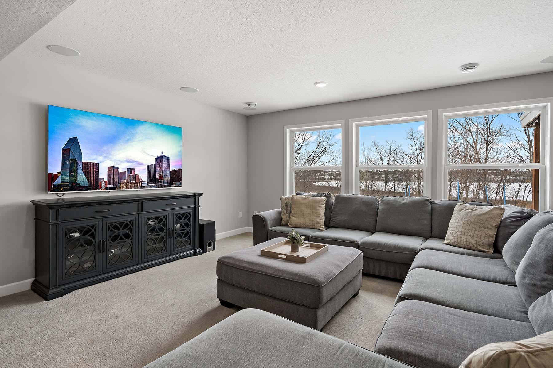 Lower-Level Family Room – This inviting expansive lower-level family room features plush carpeting underfoot and panoramic views of the backyard and outdoor patio, creating a cozy yet open space for relaxation and entertaining.