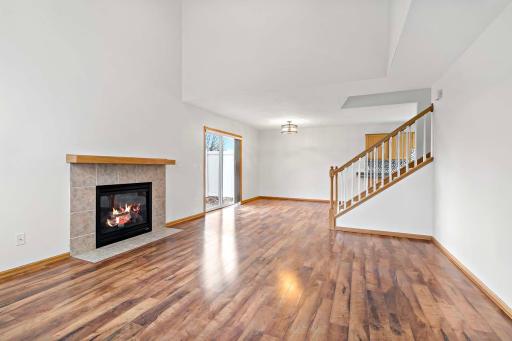 Bright, open and spacious living room with soaring ceilings, gas fireplace, and dining area overlooking patio.