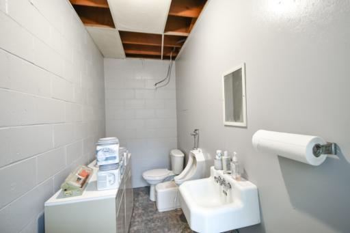 On the other side of the shower/sink wall is another bathroom with a toilet, urinal and a sink.