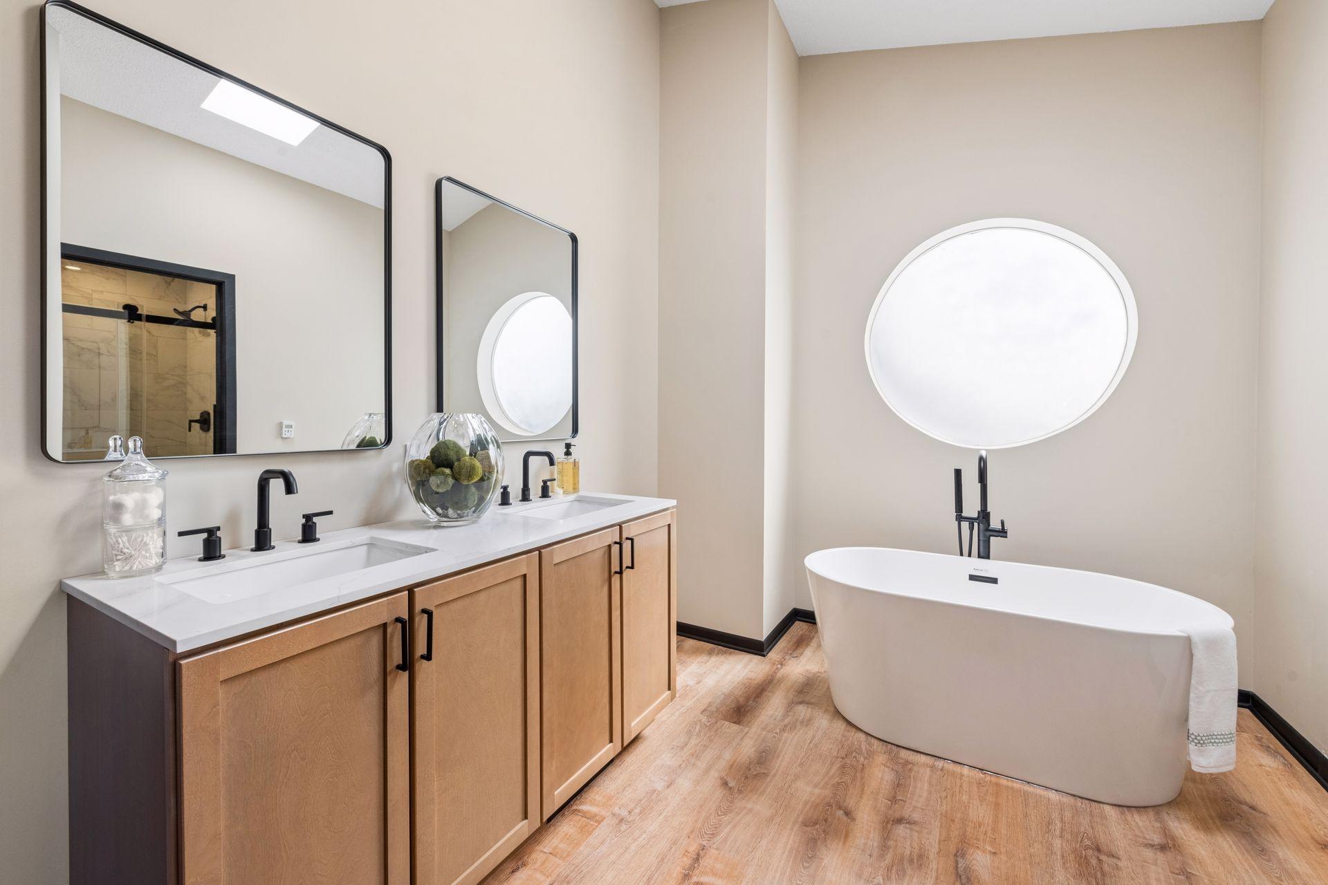 Renovated primary ensuite bath, with double vanity sinks, large free-standing soaking tub. A skylight and large frosted window offer light and privacy.