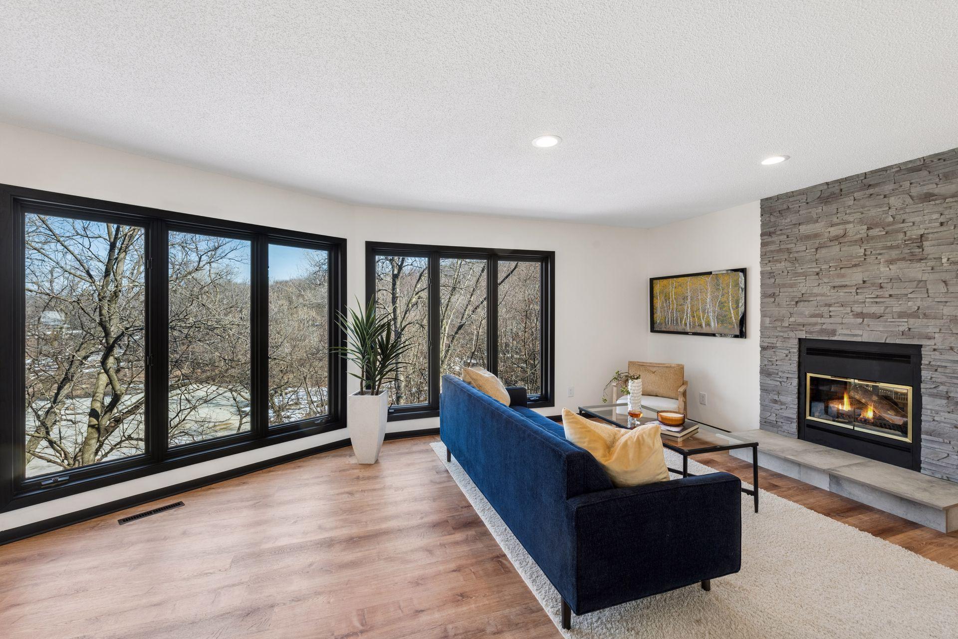 Wall of oversized windows in the front sitting room, with views of the serene pond and mature trees.