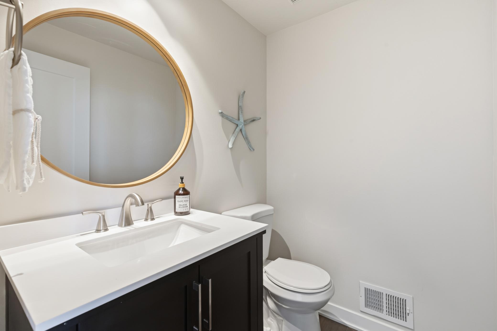 1/2 bathroom features enameled vanity with quartz countertop