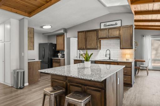 The kitchen is a standout with abundant wood cabinetry, granite countertops, a spacious center island, and black stainless steel appliances.