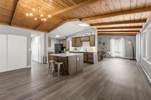 Inside, you’ll find a bright, open-concept layout featuring a vaulted wood-paneled ceiling with a skylight, a large front-facing window, and LVP flooring throughout.