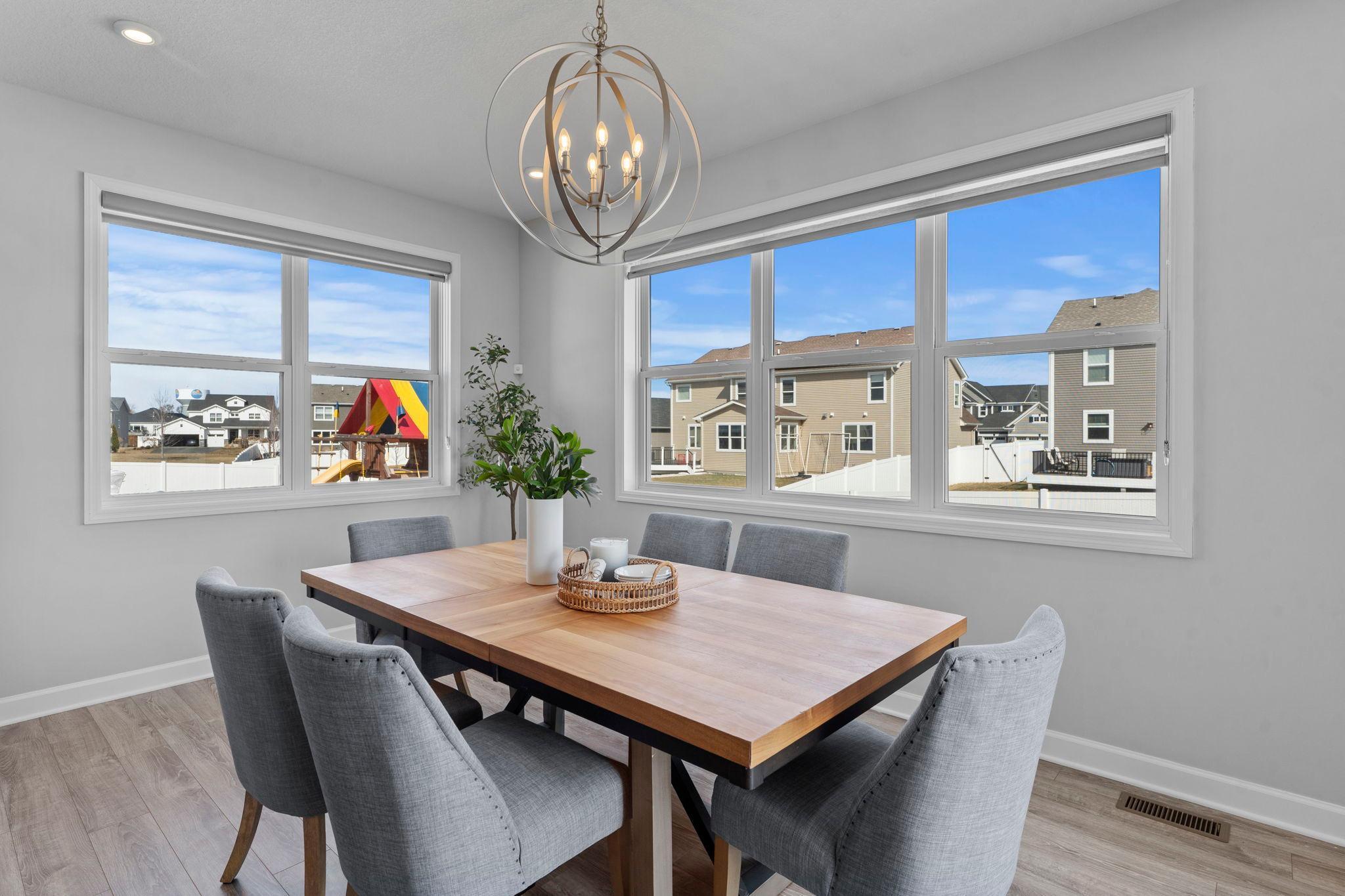 The LVP floors flow seamlessly into the dining area, which is surrounded by windows and accented by a modern chandelier, creating a bright space filled with abundant natural light.