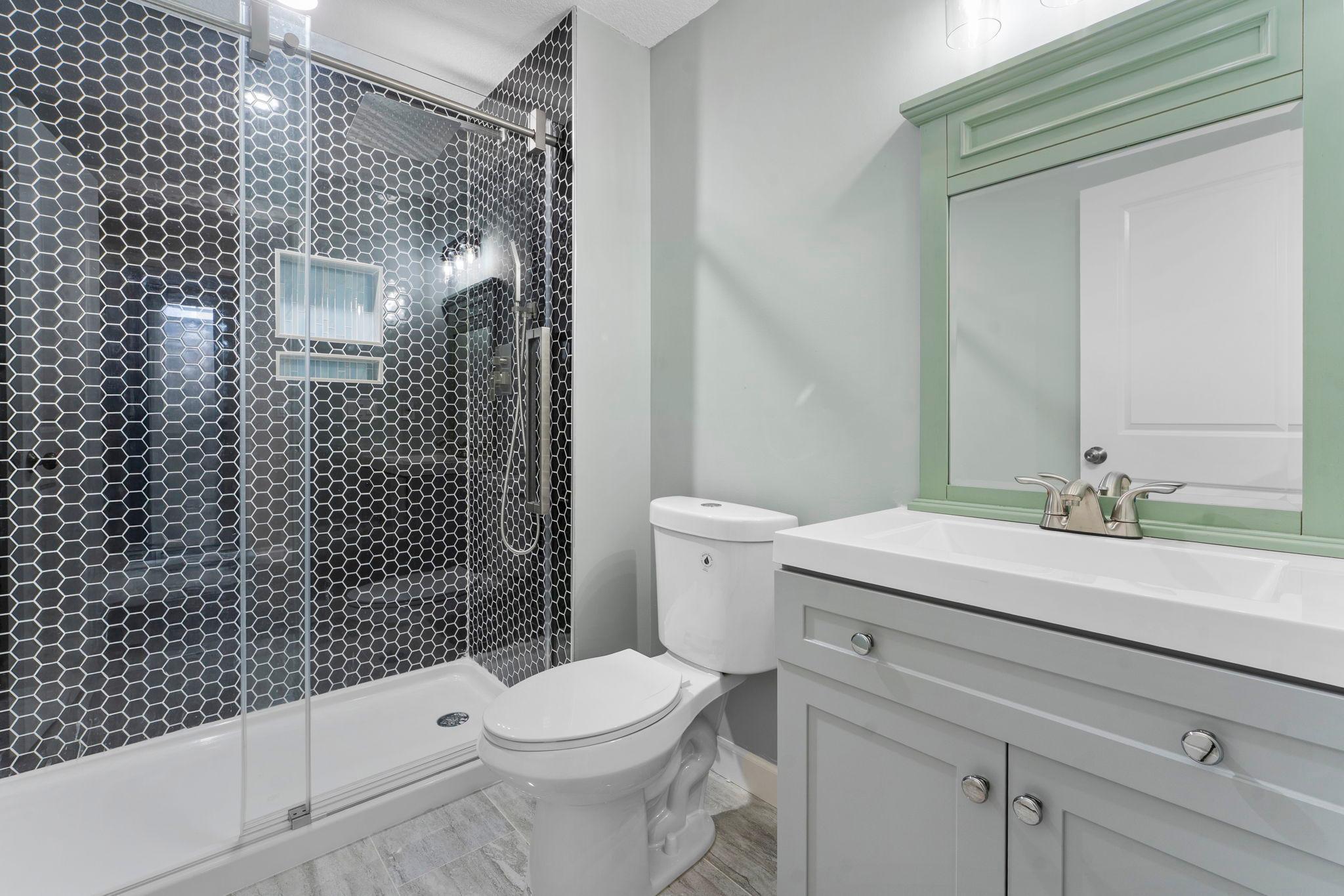 The modern lower level three-quarter bathroom featuring a walk-in shower with stylish tile surround and a single vanity.