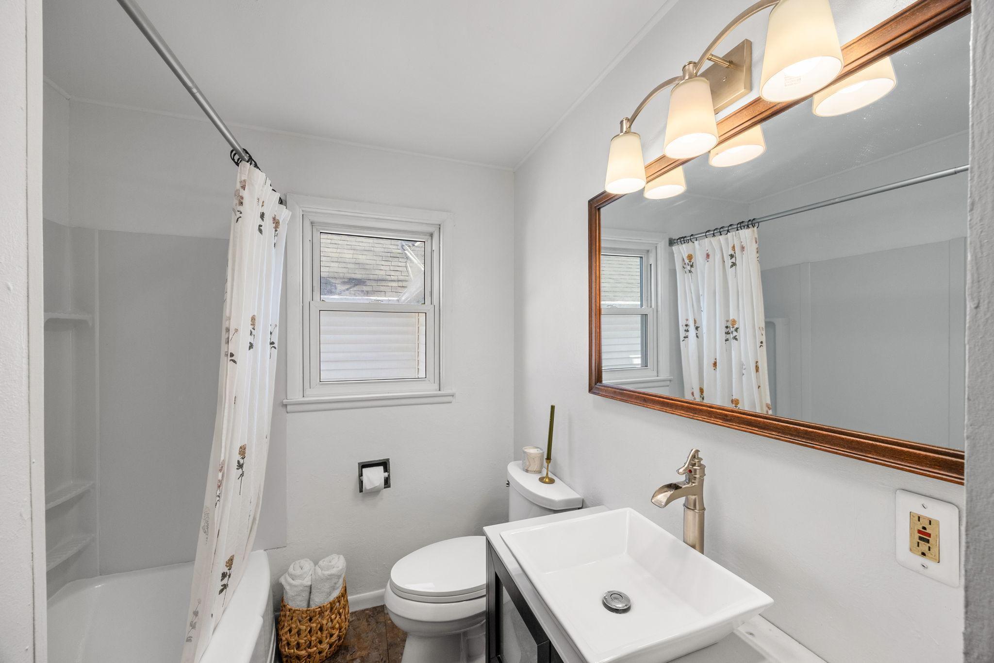 Just steps away is a shared full bathroom with a tub and shower combination, single vanity, and linen cabinet.