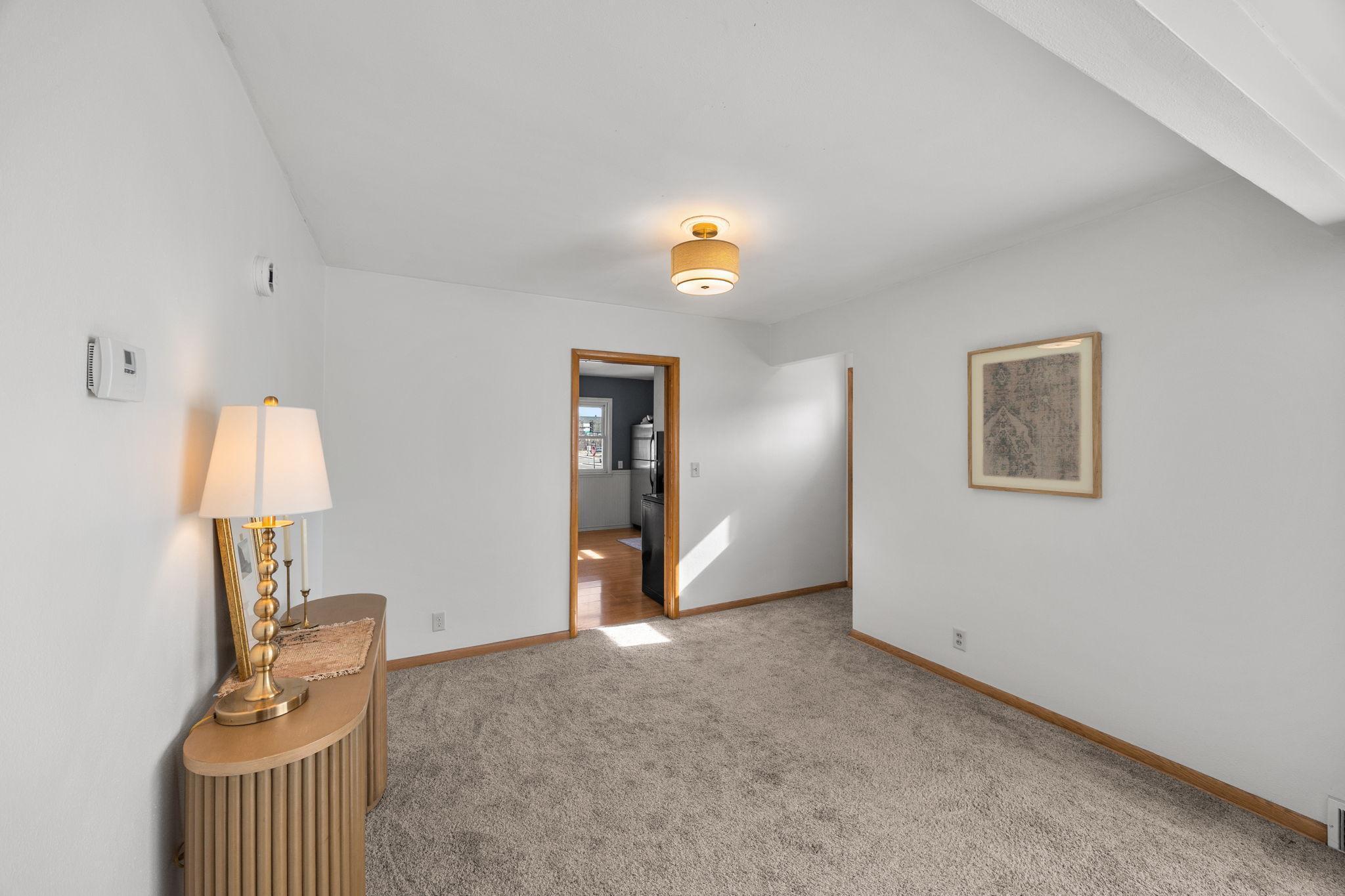 The kitchen flows seamlessly into the dining room, with carpet extending into the spacious living room.