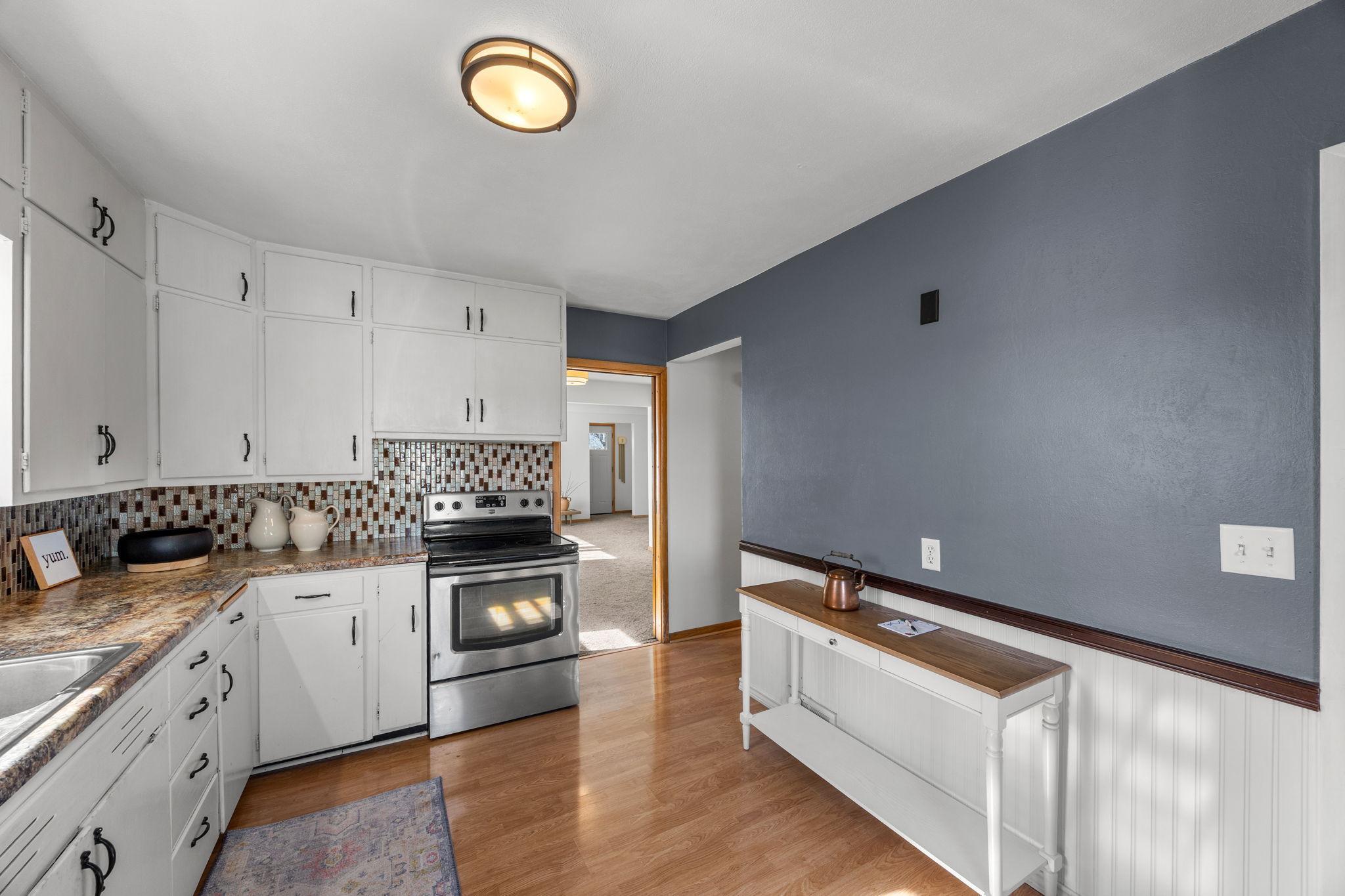 A different perspective of the kitchen, showcasing the entrances to the dining and living areas, as well as the hallway leading to the main floor bedrooms.
