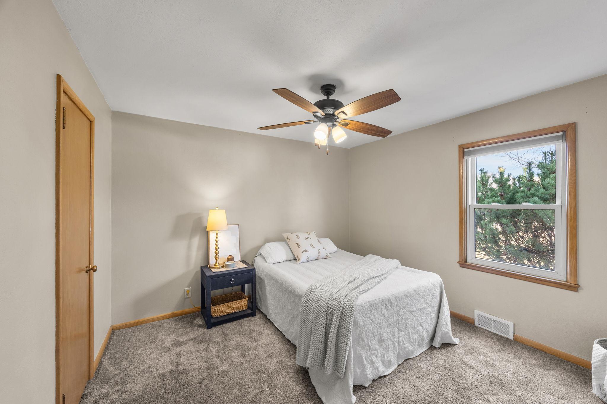 Main-level bedroom featuring a ceiling fan, carpeted floors, and ample closet space.