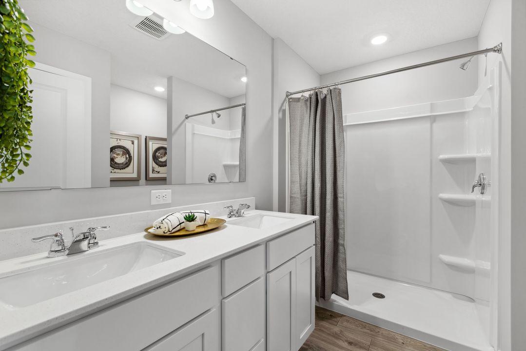 Primary bath features large vanity with dual sinks and quartz countertops. Photo of model home. Colors and options may vary.